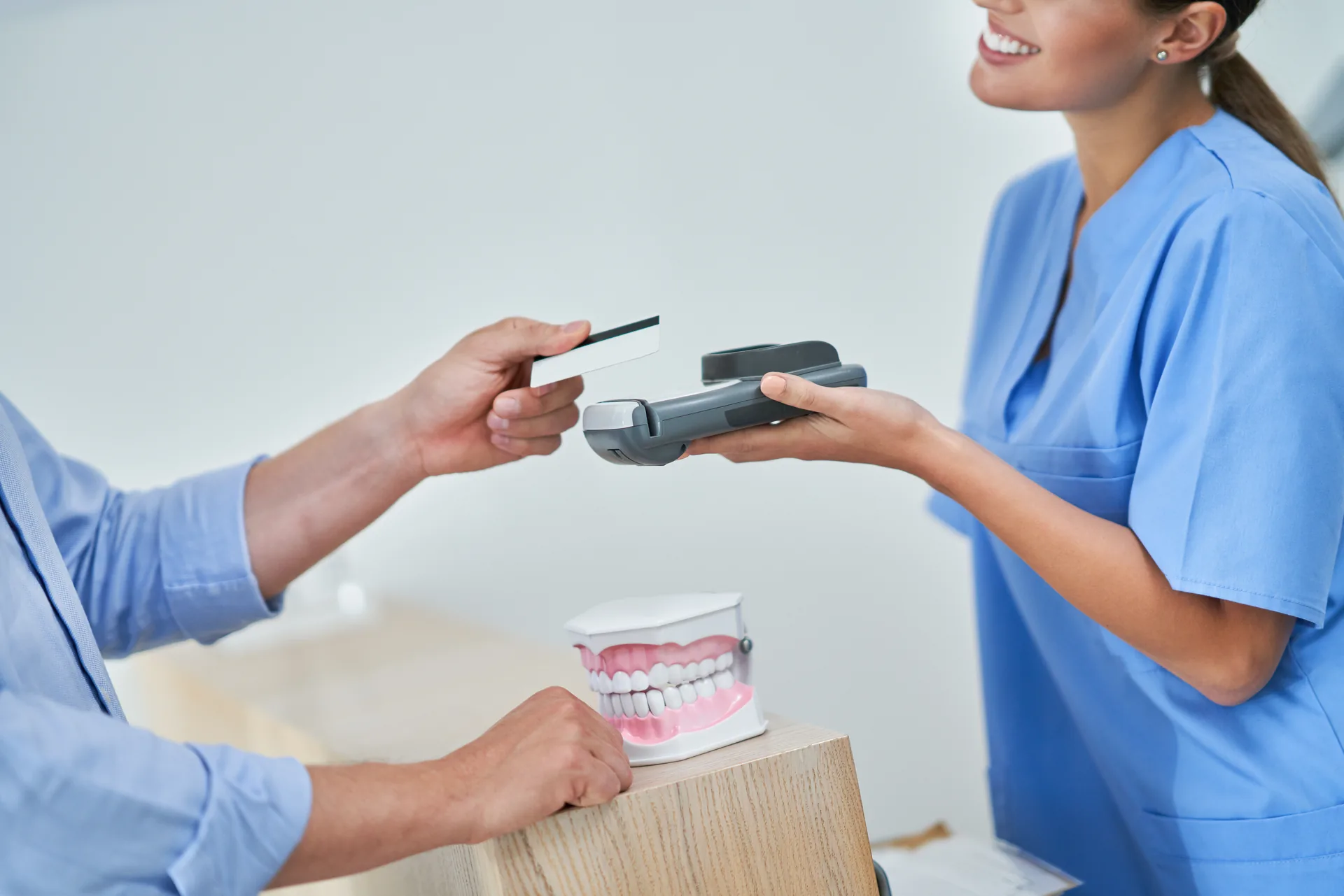 Dental staff assisting a patient with payment at the front desk in a modern dental clinic