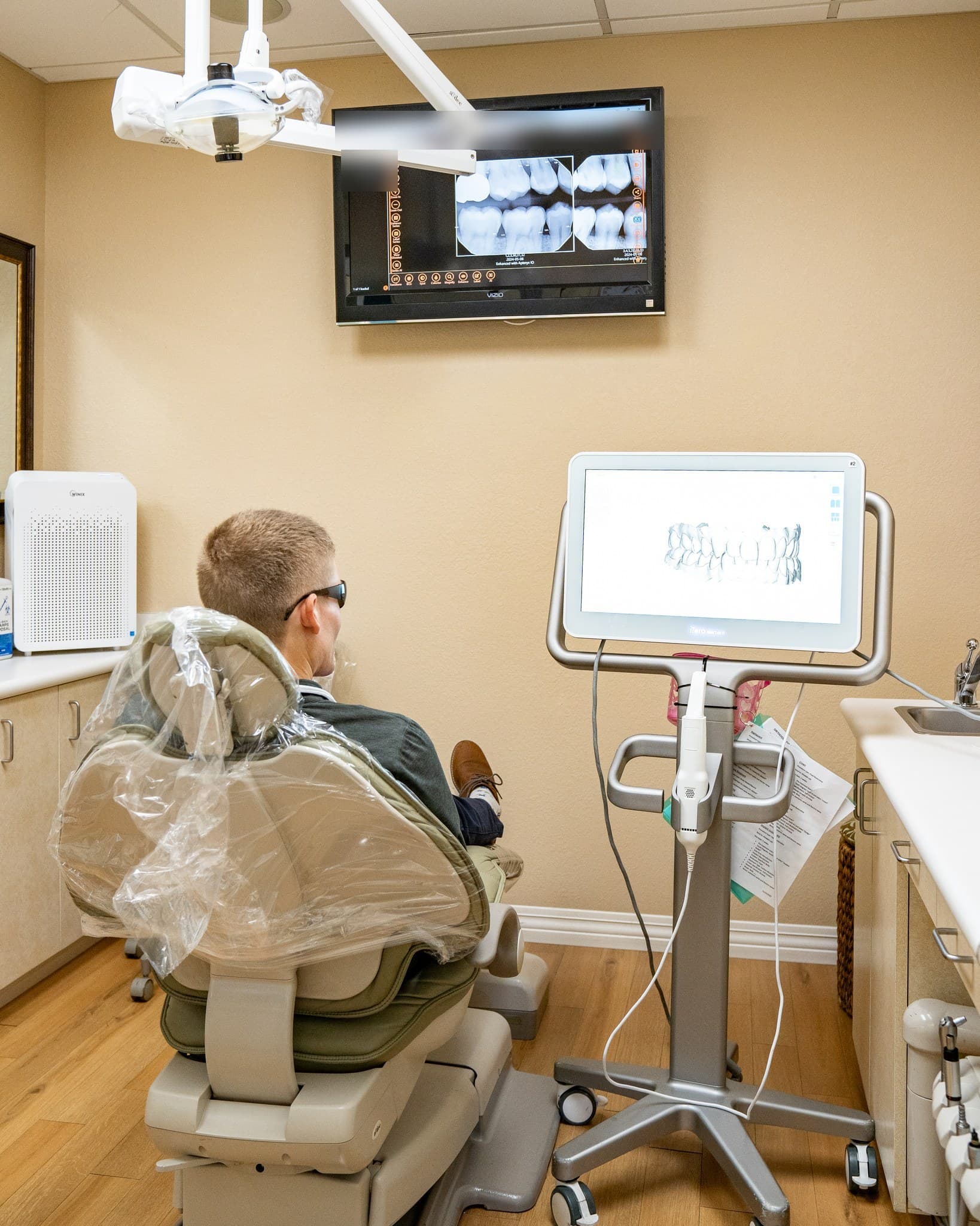 A patient relaxes in a treatment chair at J Street Dental Group, a sedation dentist in Sacramento, with x-rays on the wall screen and a digital scanner beside the chair