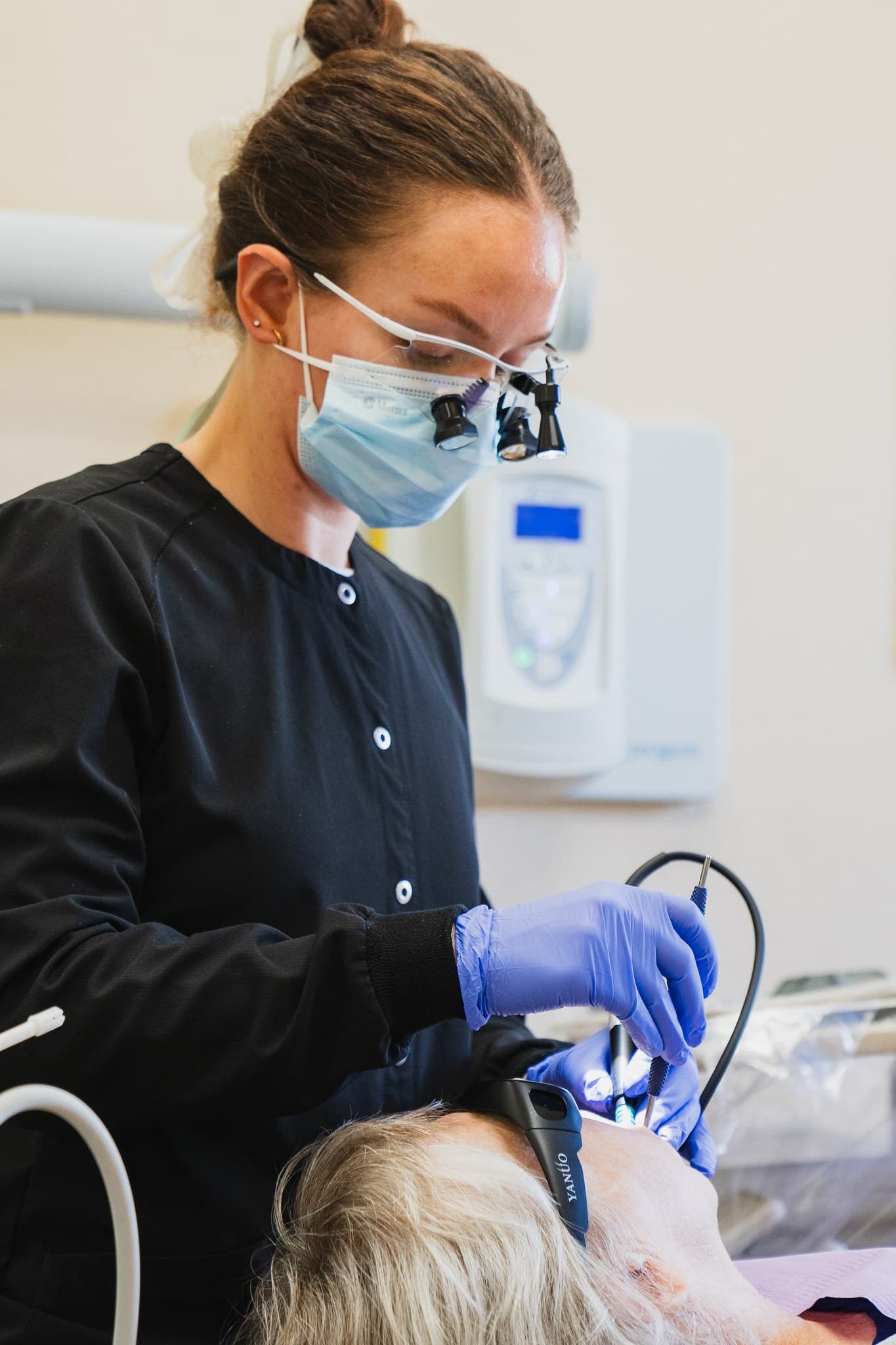 A J Street Dental Group hygienist wearing magnifying loupes cleans a patient's teeth during gum disease treatment in Sacramento